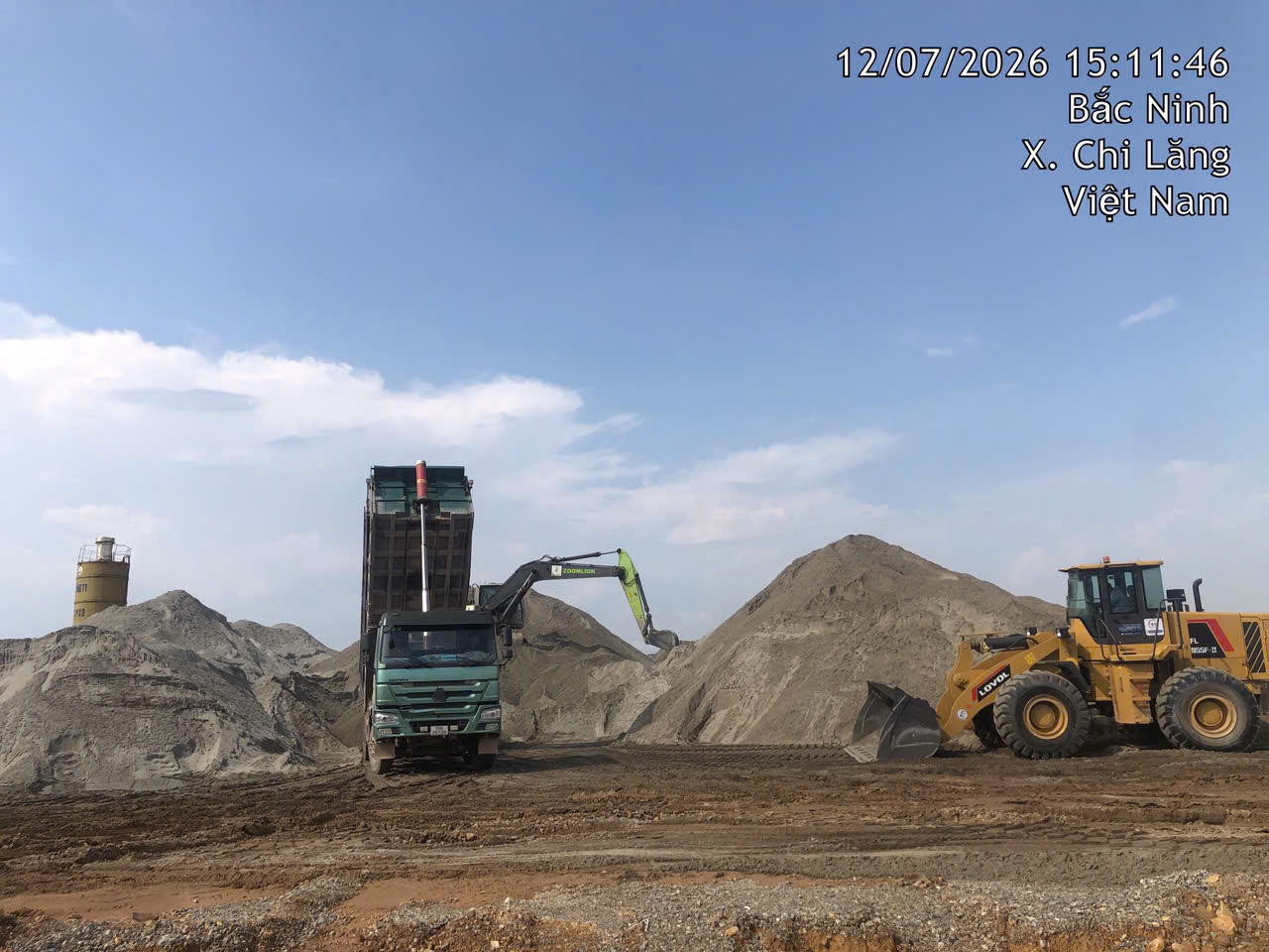 Xe tải và máy xúc đang làm việc tại bãi vật liệu trạm bê tông